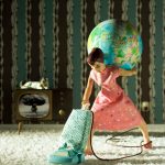 Figurine of a woman vacuuming and holding a globe on her back. The TV in the background shows an atomic bomb exploding.
